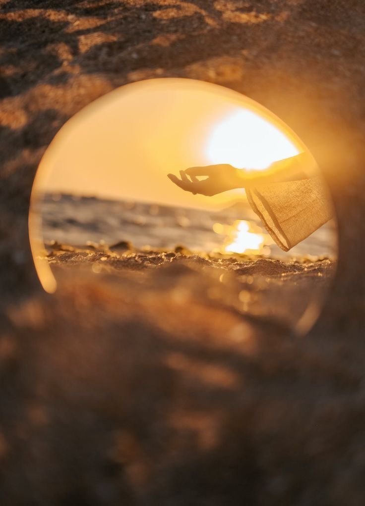 夕日の海辺で、丸い枠の中に映る差し伸べた手